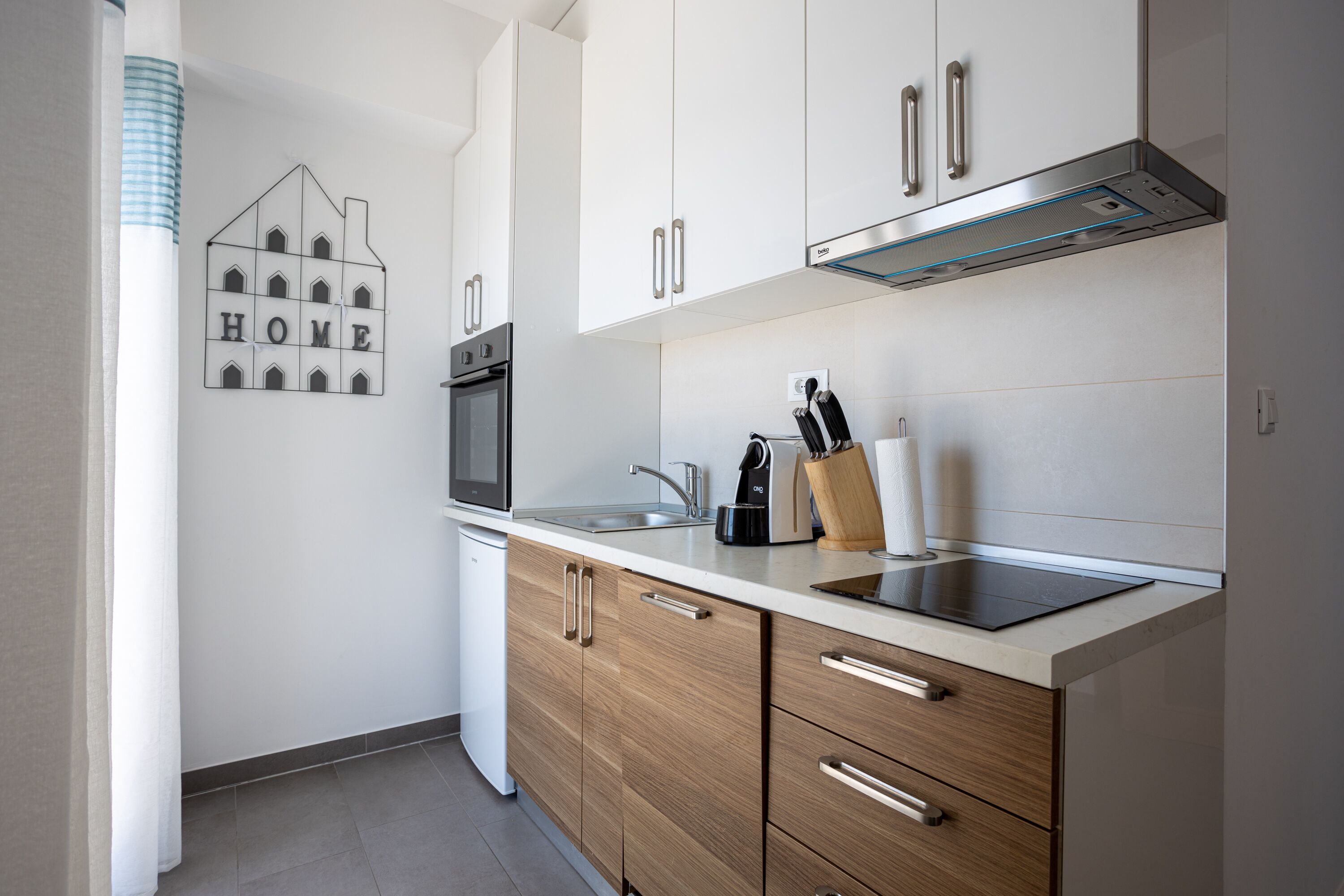 Een moderne keuken met witte kasten, roestvrijstalen apparatuur en houten lades.