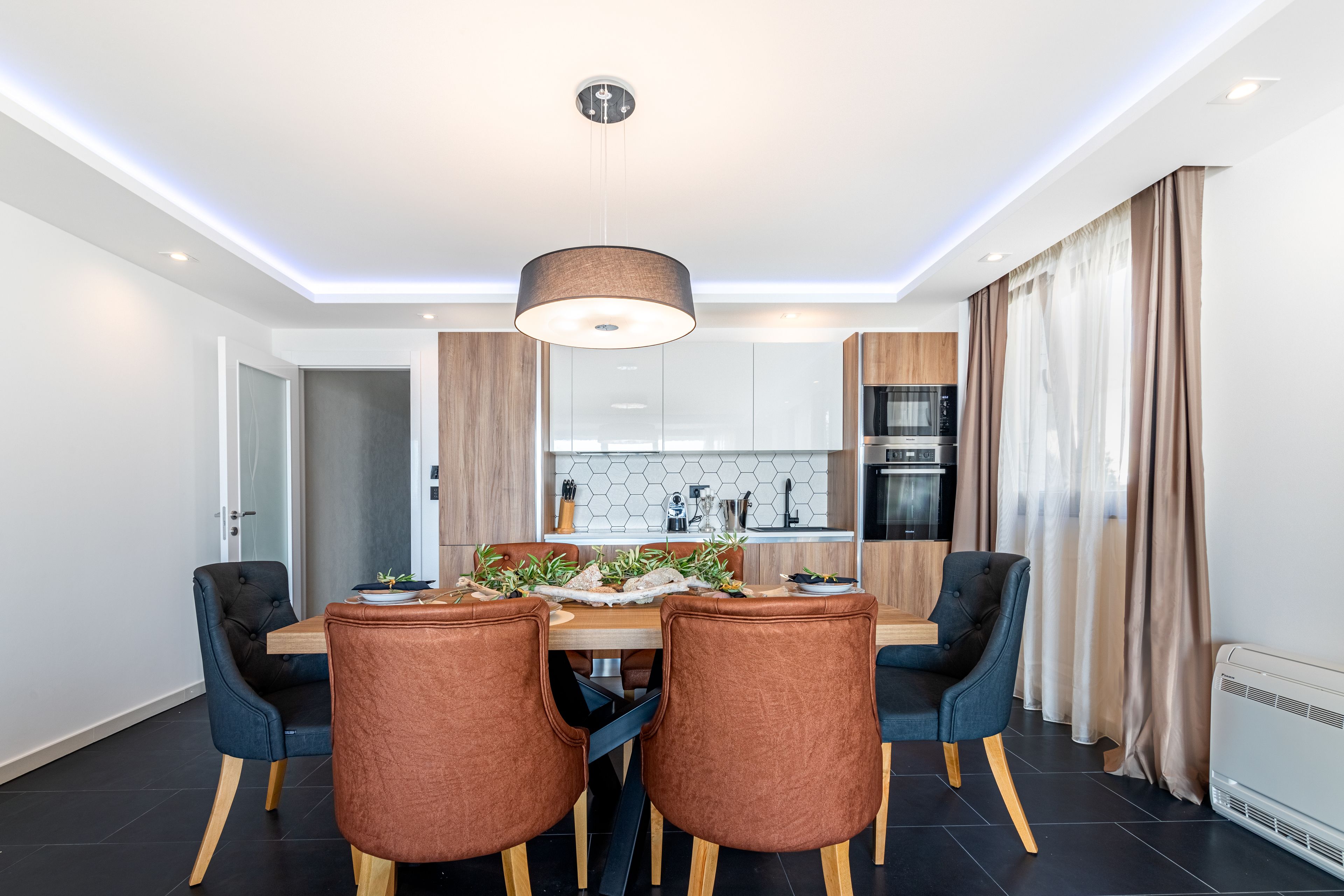 A modern dining area with a wooden table, four chairs, and a pendant light.