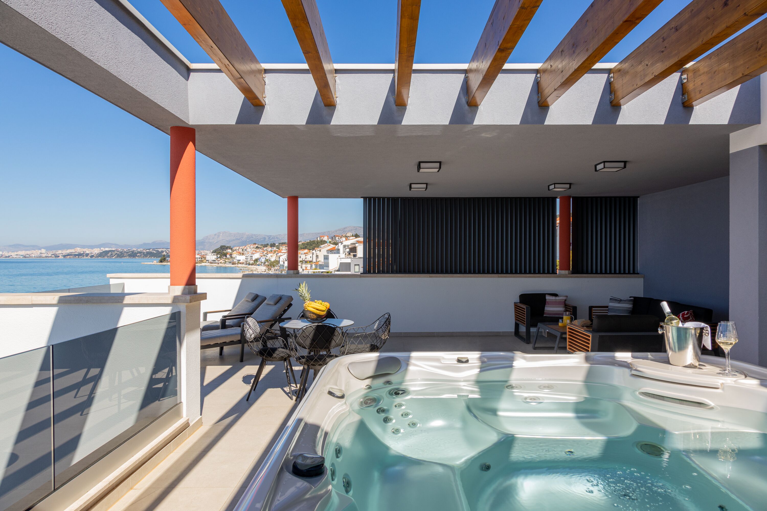 A rooftop terrace with a hot tub, outdoor seating, and a view of the sea.