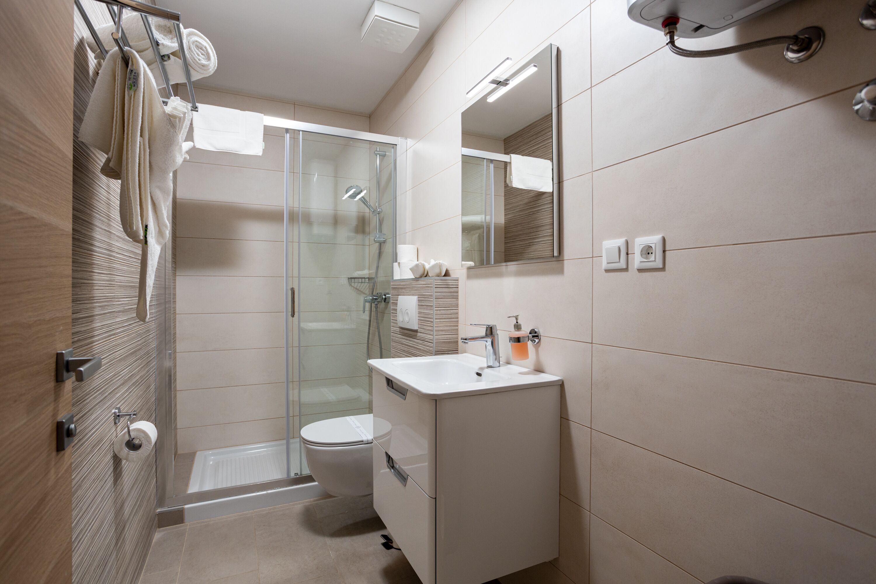 A modern bathroom with a glass shower enclosure, a white toilet, and a vanity with a mirror.