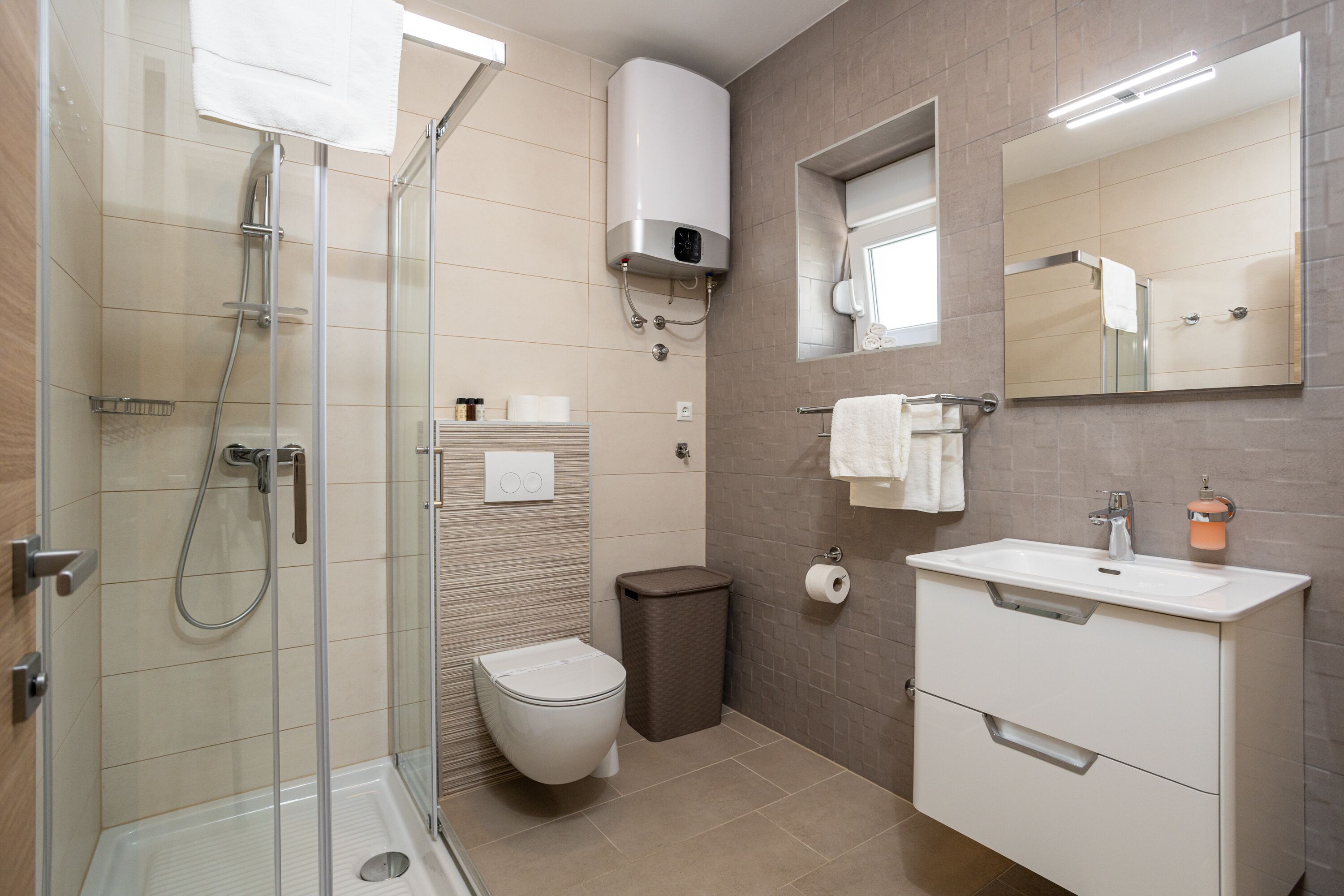 A modern bathroom with a glass shower enclosure, a toilet, a sink with a mirror, and a towel rack.