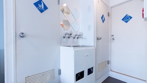 A clean, modern bathroom with a sink, mirror, and toilet. There are signs indicating the locations of the toilet and shower room. - LUANA Nakano (Tokyo)