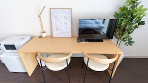 A wooden desk with a framed picture, a black monitor, two white chairs, and a plant. - LUANA Nakano (Tokyo)