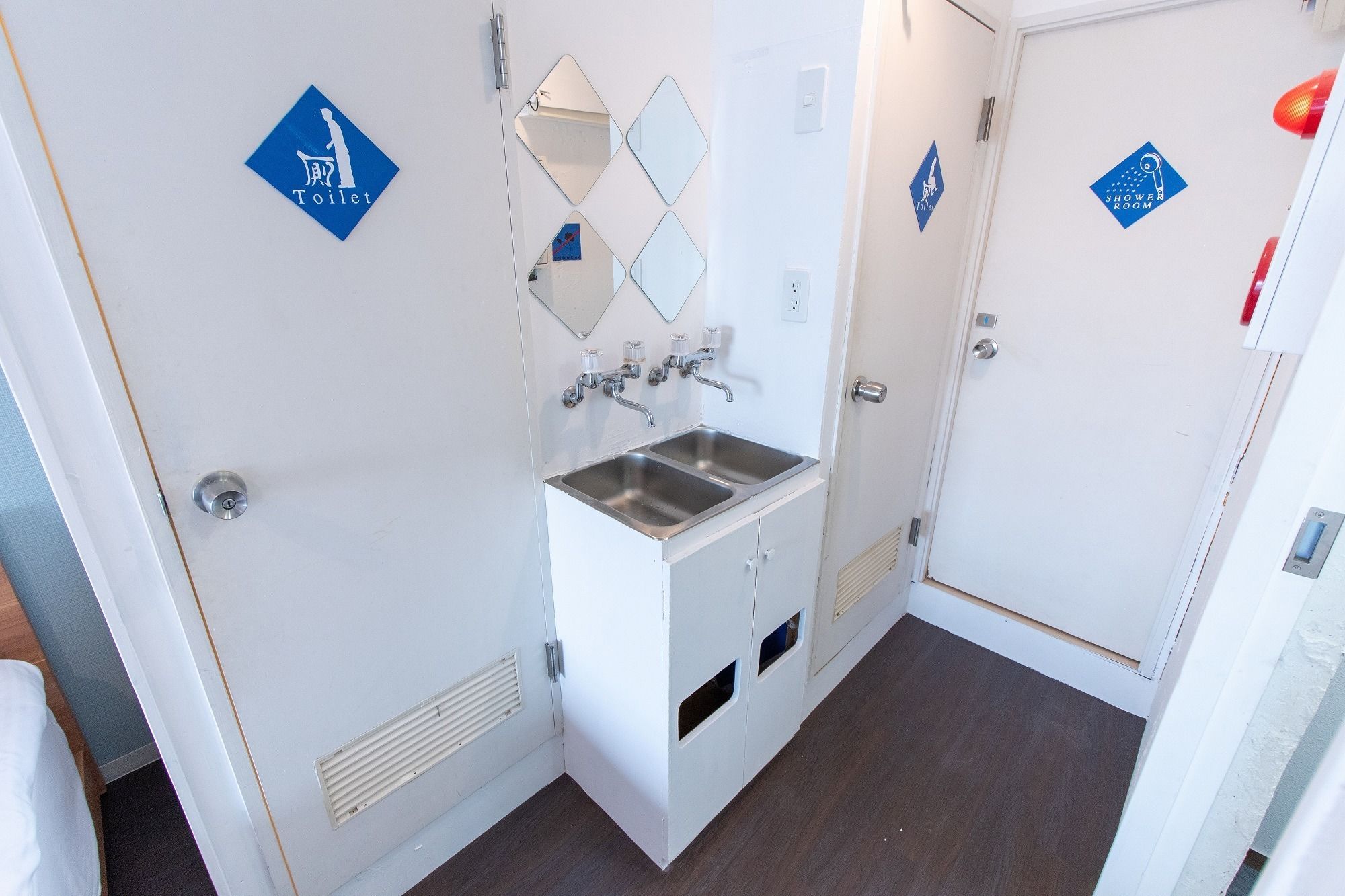Un baño pequeño y estrecho con un lavamanos, dos espejos y un inodoro.