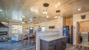 A modern kitchen with a central island, stainless steel appliances, and a dining area with a fireplace.