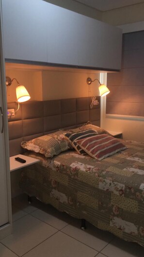 Une chambre à coucher avec un lit, deux lampes de chevet, une table de chevet et une fenêtre.