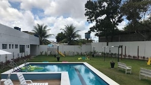 Et rektangulært swimmingpool med træterrasse og hvide liggestole.