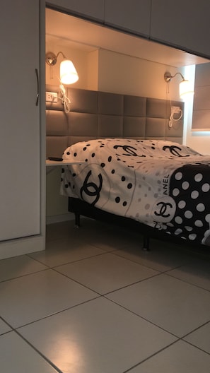 Une chambre à coucher avec un lit, une table de chevet, une lampe et une tête de lit.