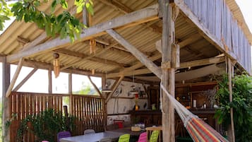 A wooden deck with a table and chairs, a hammock, and a green artificial turf area.