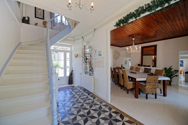A staircase leading to a dining area with a geometric patterned floor, a chandelier, and a wooden ceiling. - Le Kouloury (Meyronne)