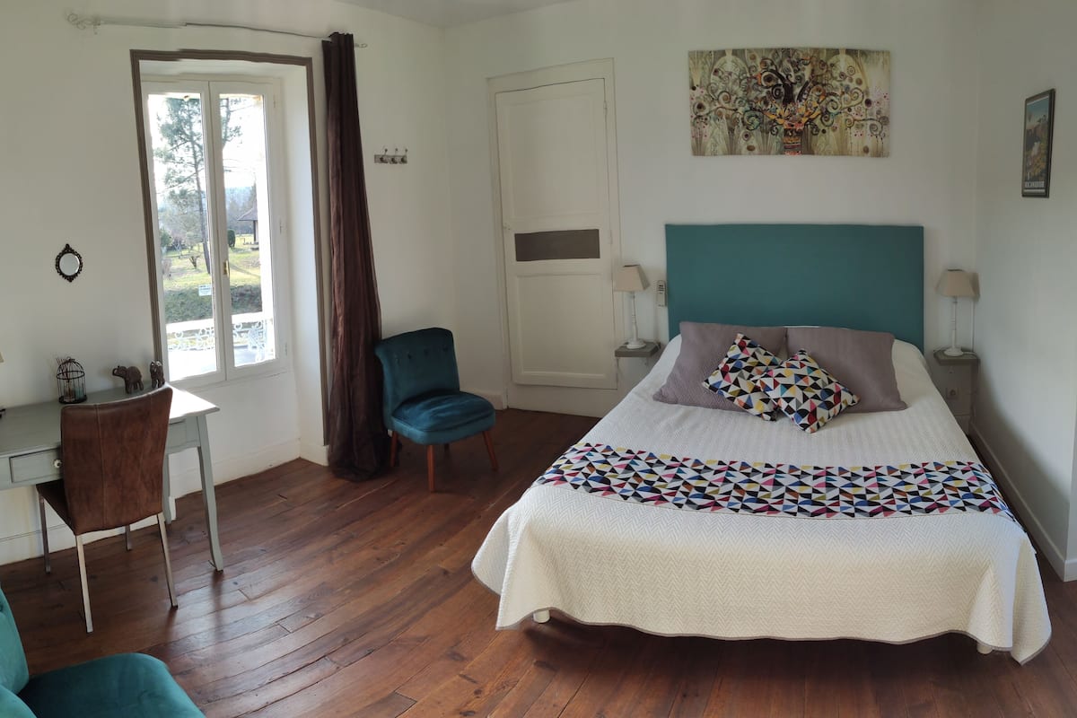 Ein Schlafzimmer mit Bett, Schreibtisch, Stuhl und einem Fenster mit Vorhängen.