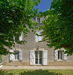 A building with a stone facade, white shutters, and a visible window. - Le Kouloury (Meyronne)