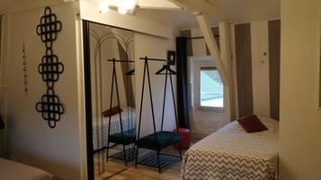 A bedroom with a bed, a hanging chair, a window, and a door.