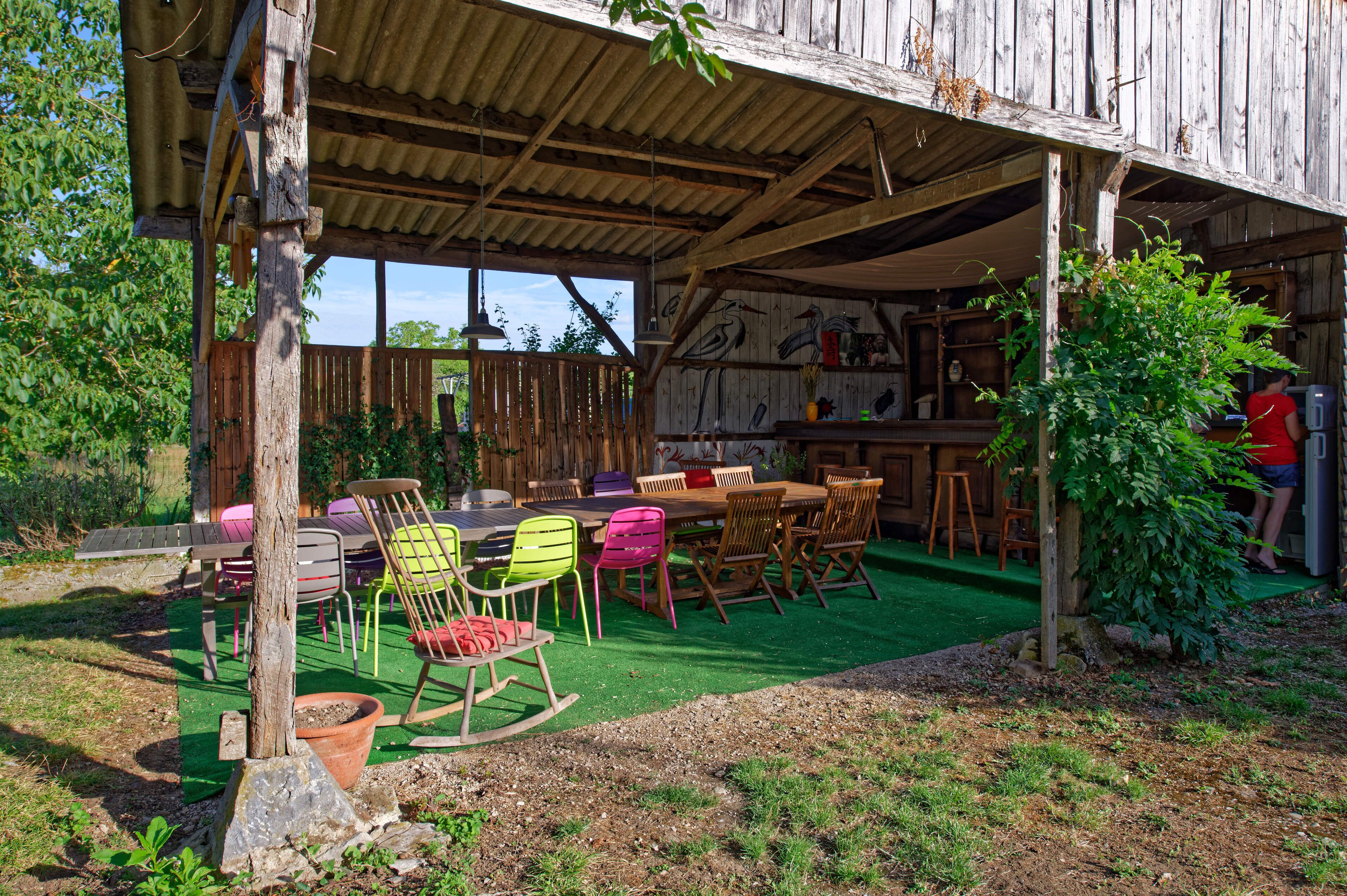 Een buiten eetgedeelte met een overdekte patio, houten meubels en kunstgras.