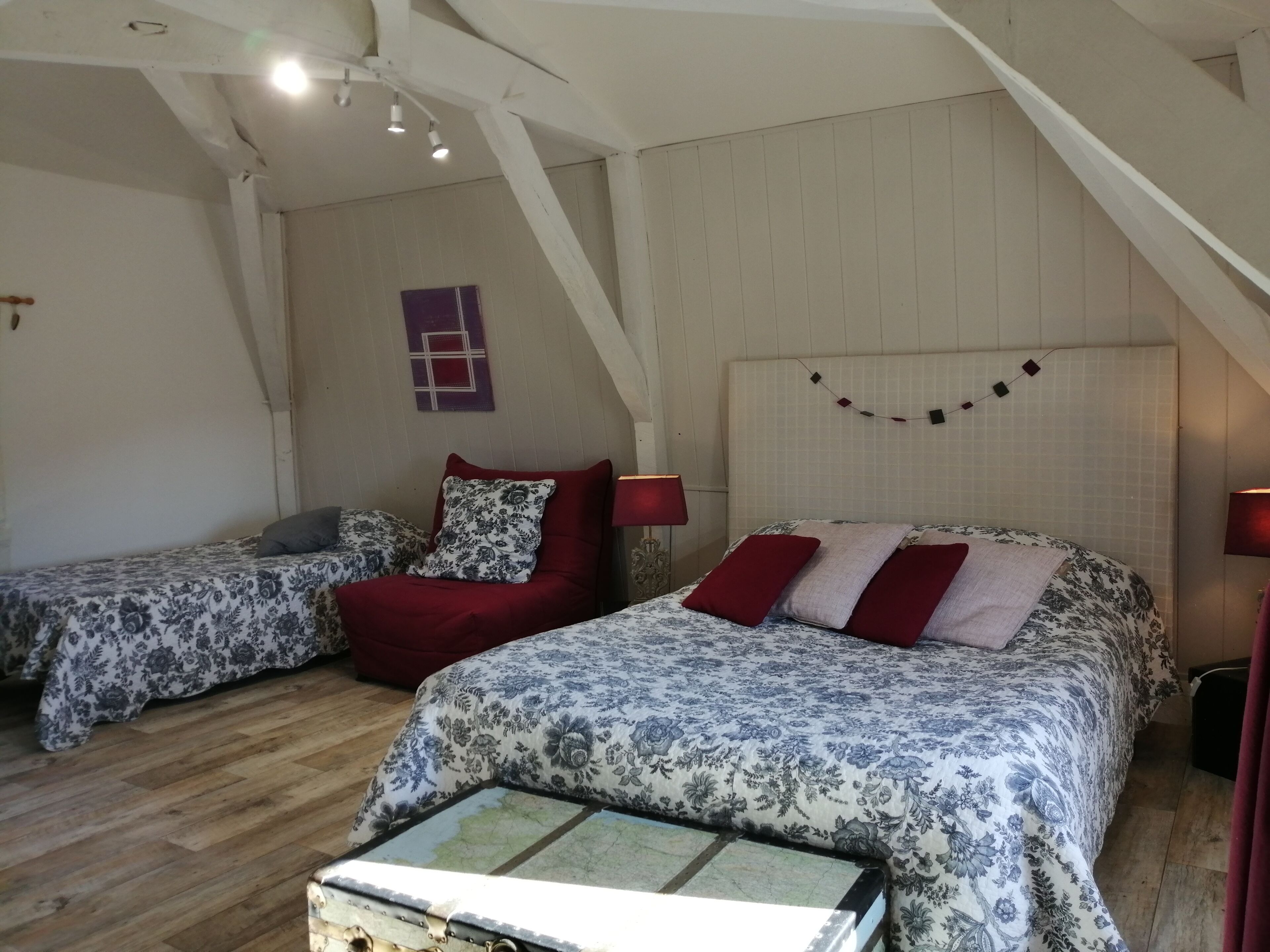 A bedroom with two beds, a wooden floor, and a sloped ceiling.