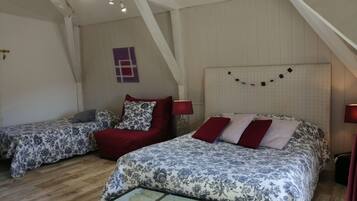 A bedroom with two beds, a wooden floor, and a sloped ceiling.