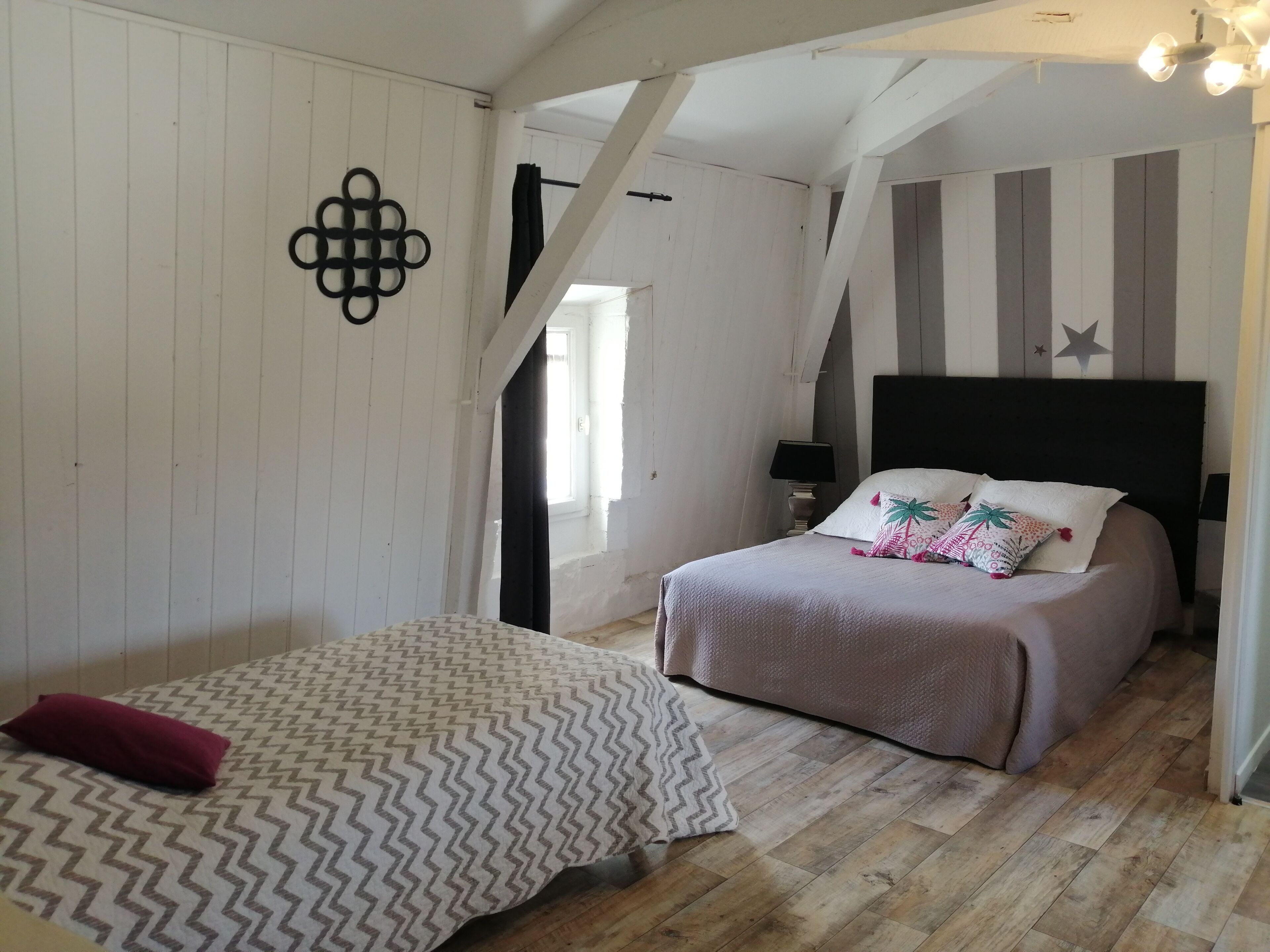 Un dormitorio con dos camas, suelo de madera, un adorno en la pared con forma de estrella y un diseño de rayas en la pared.