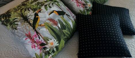 Una cama con almohadas de estampado floral y una almohada de diseño oscuro.