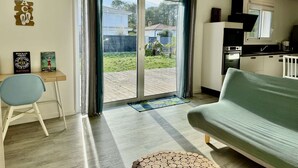 A modern living room with a sofa, a dining table, and a kitchen area. - VillasHomeClet - Villa Les Alizés ⭐️ Terrace ⭐️ Beach ⭐️ A/C ⭐️ 3 bedrooms (VENSAC)