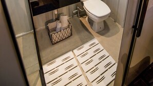 Un baño moderno con encimera negra, inodoro blanco y cabina de ducha de vidrio.