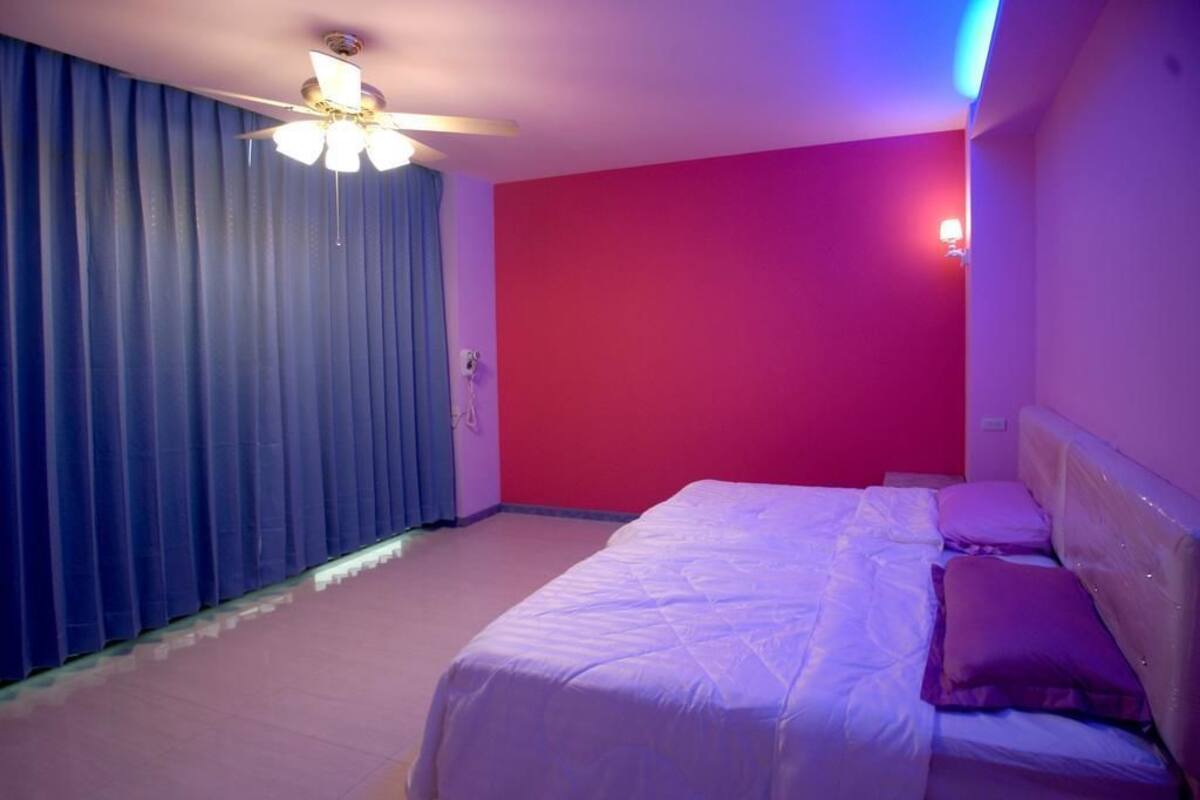 Ein Schlafzimmer mit einem Bett, einem Deckenventilator und einer roten Wand.