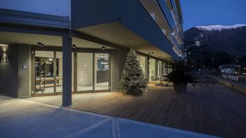 A modern building with a glass facade, a wooden deck, and a Christmas tree.