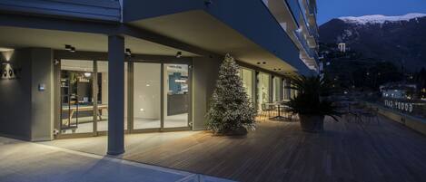 Ein modernes Gebäude mit Glasfassade, einer Holzterrasse und einem Weihnachtsbaum.