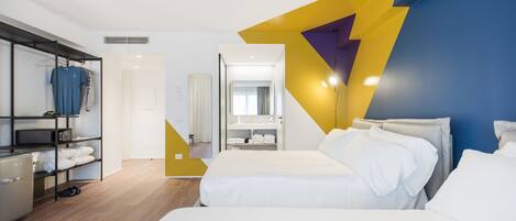 A modern hotel room with a large bed, a wardrobe, and a bathroom visible through an open door.
