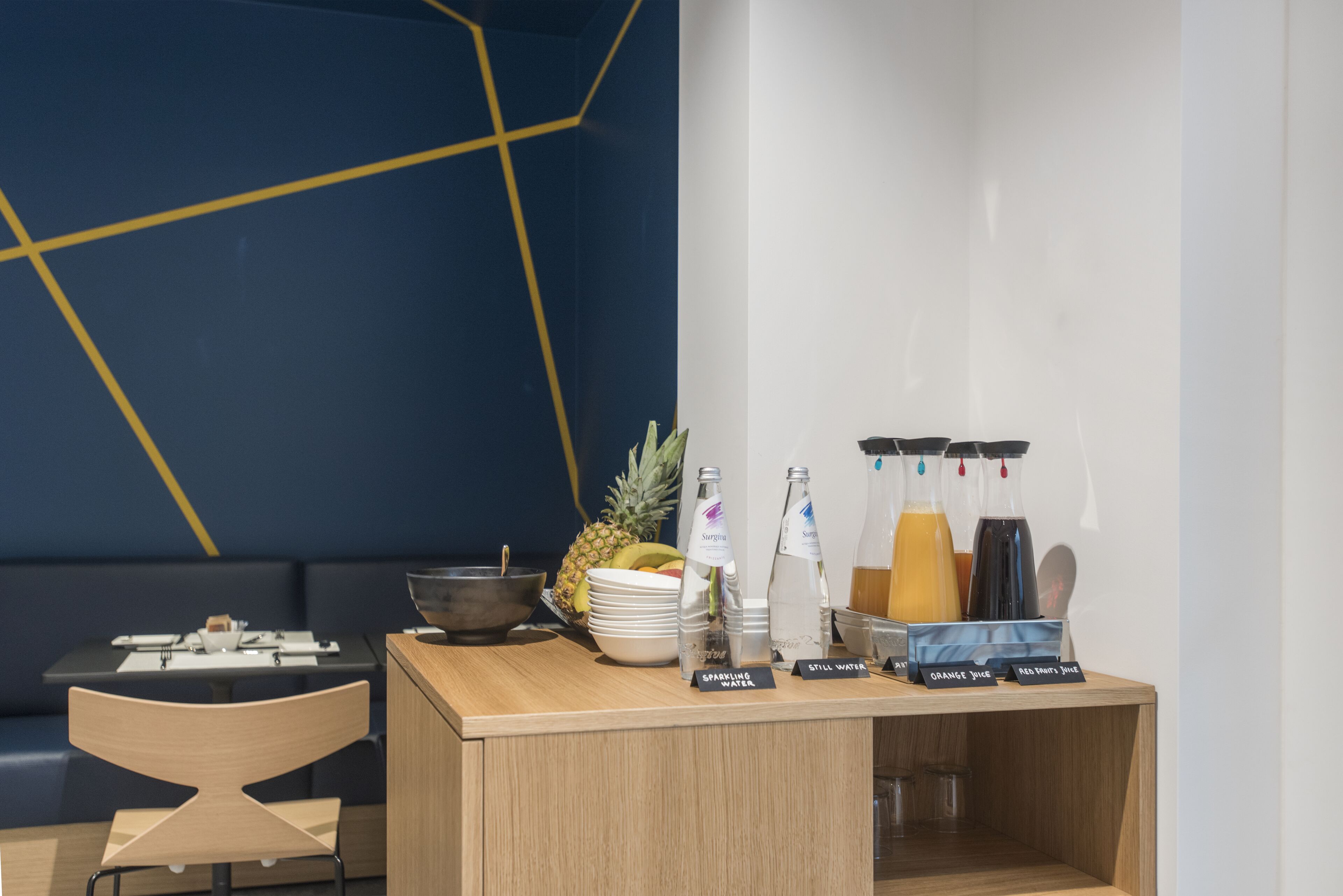 Un área de recepción con un mostrador de madera, una piña y dispensadores de bebidas etiquetados.