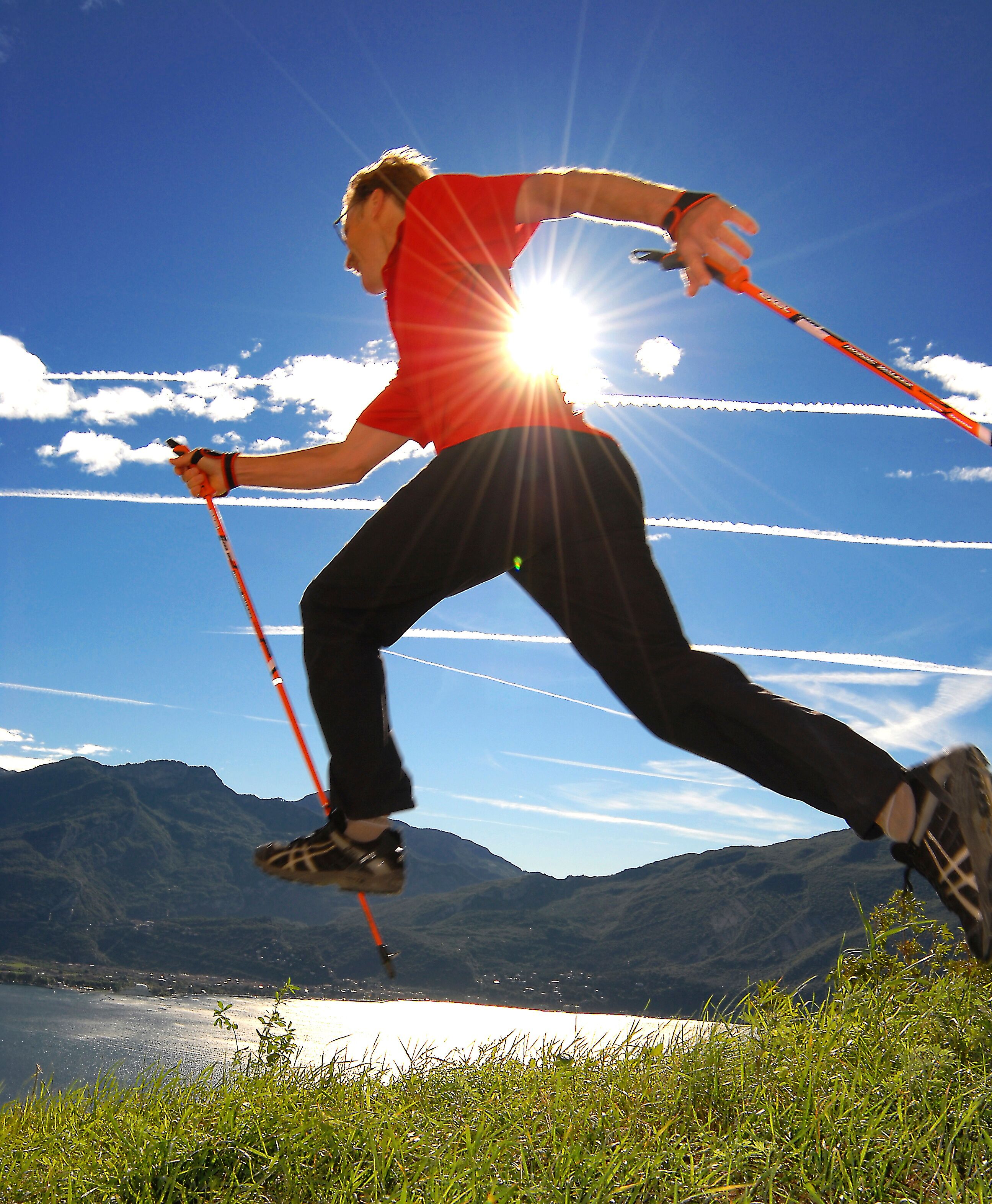A person skiing on a clear day with mountains and a lake in the background.