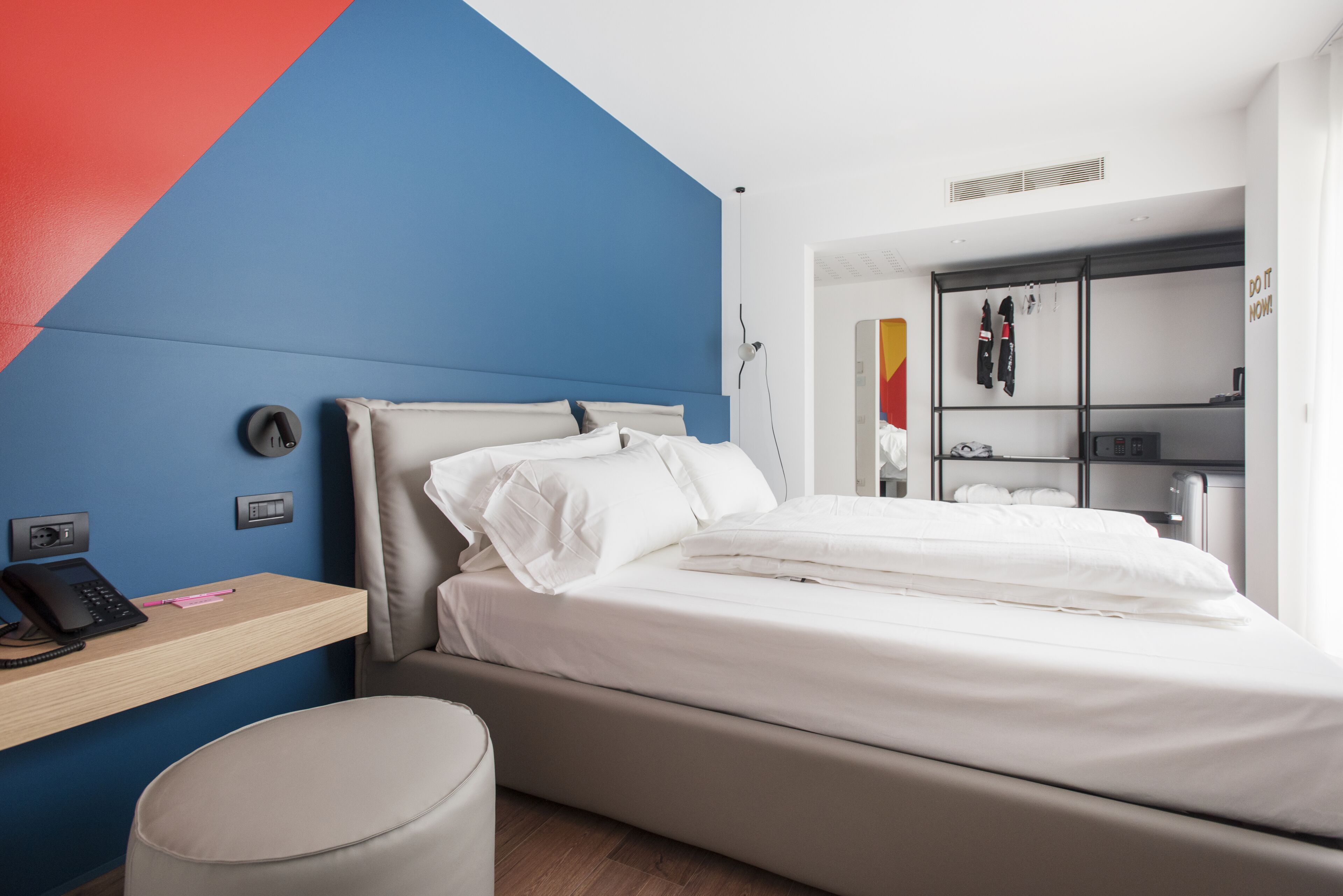 A modern bedroom with a bed, a desk, and a wardrobe.