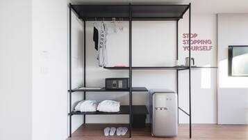 A compact room with a bed, a small desk, a microwave, and a refrigerator.