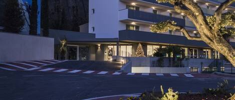 Um hotel moderno com vários andares, uma entrada bem iluminada e um pinheiro de Natal.