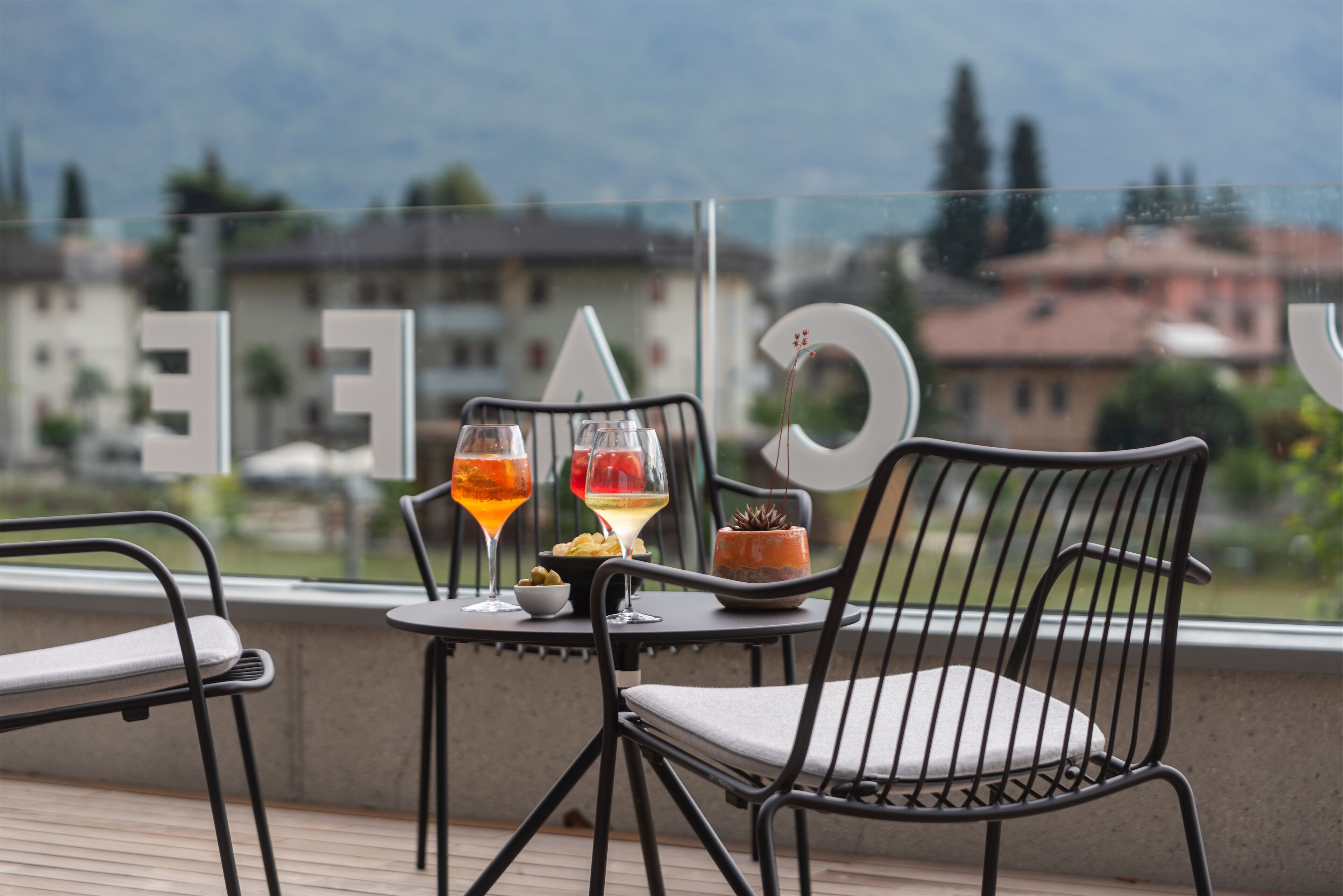 A terrace with a table set for two, featuring two glasses of wine and a small bowl of snacks.