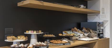A buffet setup with various baked goods and pastries on display.