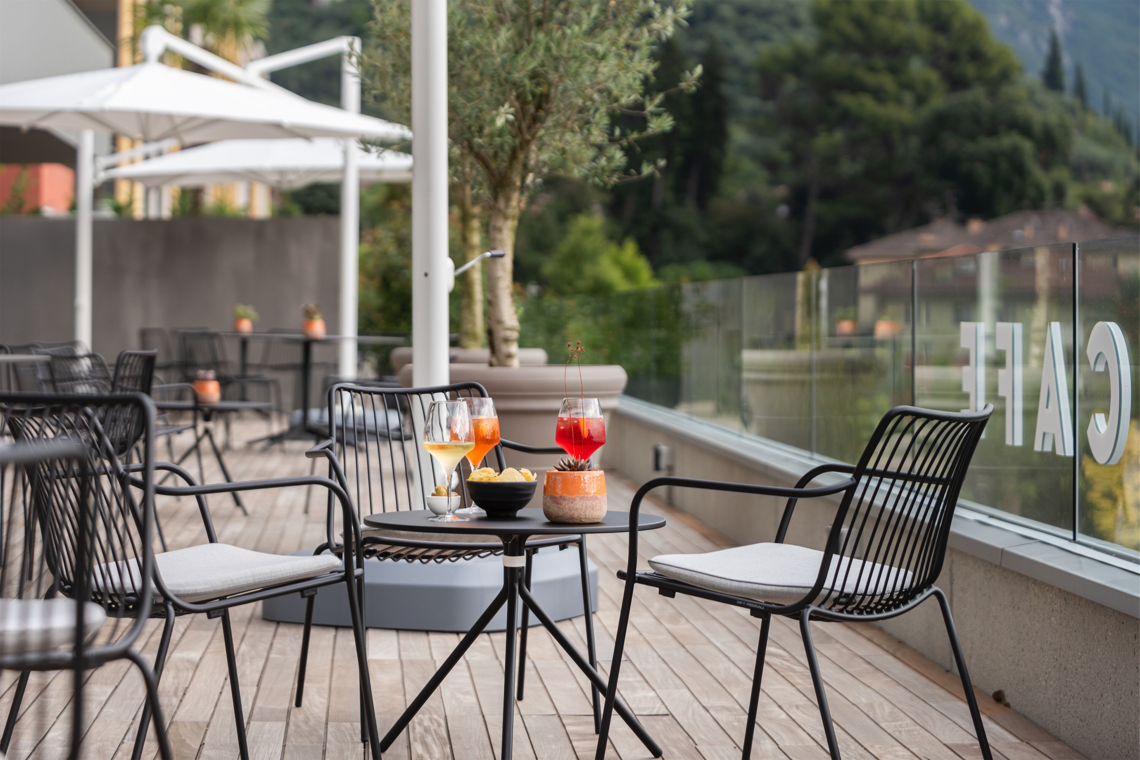 An outdoor seating area with tables and chairs, a bowl of snacks, and two drinks on a table.