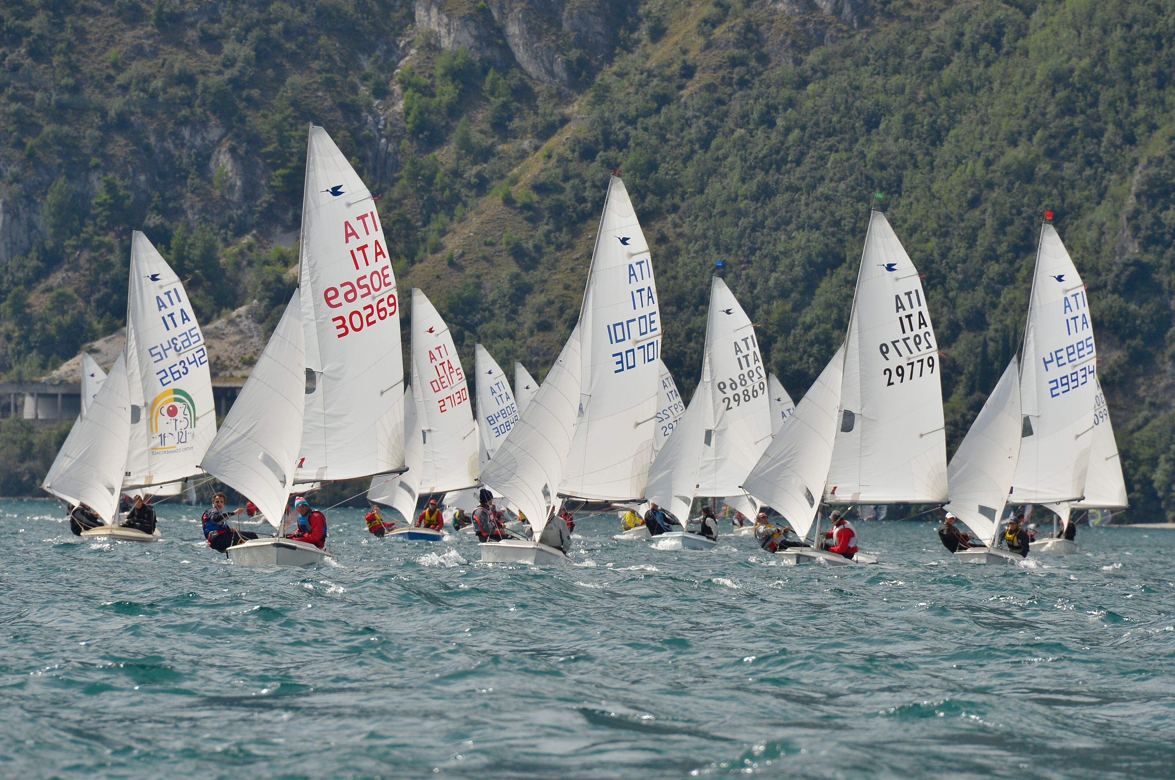 Eine Gruppe Segelboote auf dem Wasser, mit Bergen im Hintergrund.