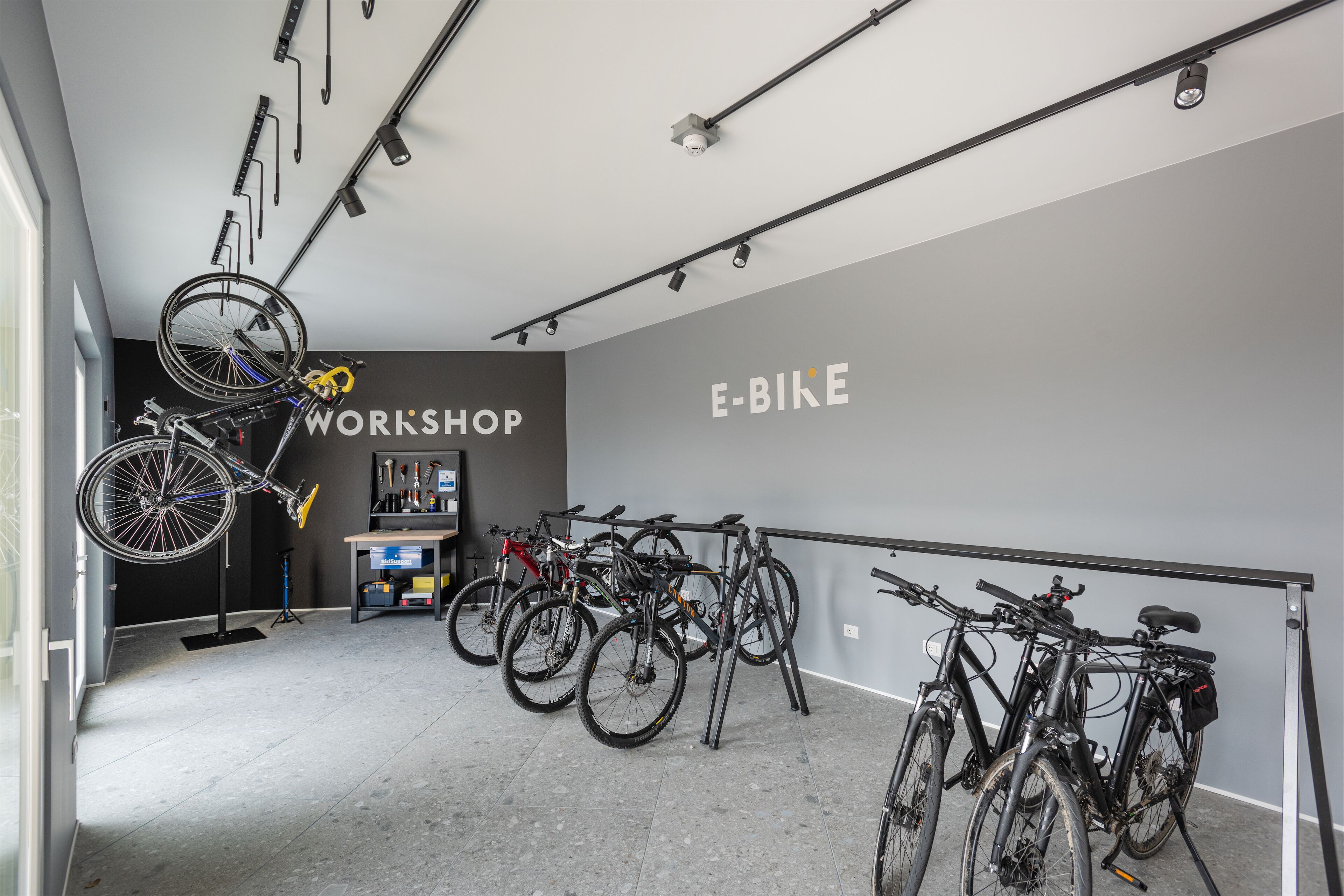 A bike workshop with multiple bicycles, a workbench, and tools.