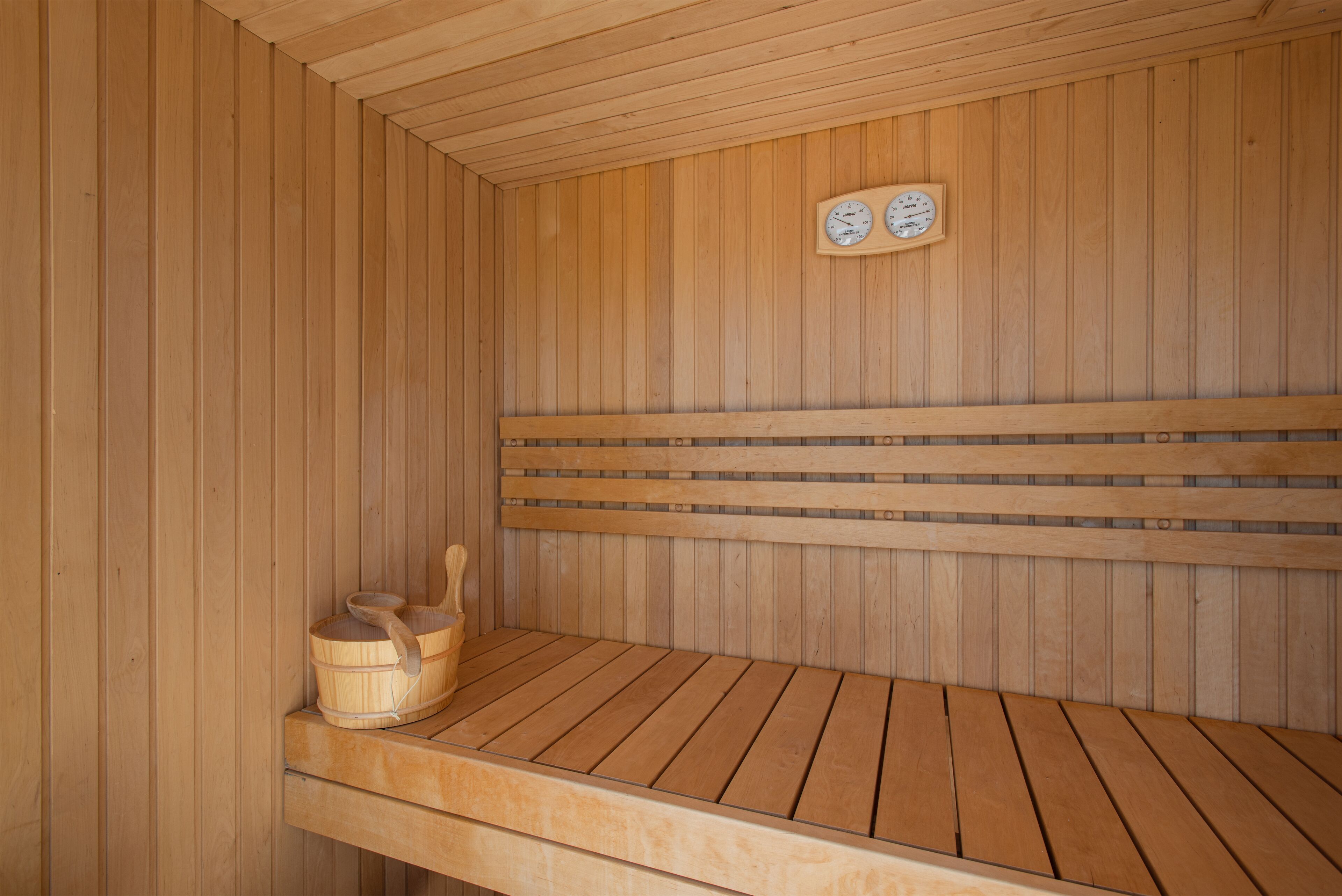 A wooden sauna with benches and a wooden bucket.