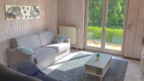 Un salon moderne avec un canapé gris, un canapé plus petit, une table basse et un radiateur.