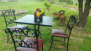 Ein Sitzbereich im Freien mit Tisch und Stühlen, einer Obstschale und einem Glas Orangensaft.
