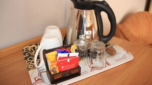 Eine Kaffeestation mit Wasserkocher, Tassen, Zuckerportionen und Salzdosen auf einem Tisch.