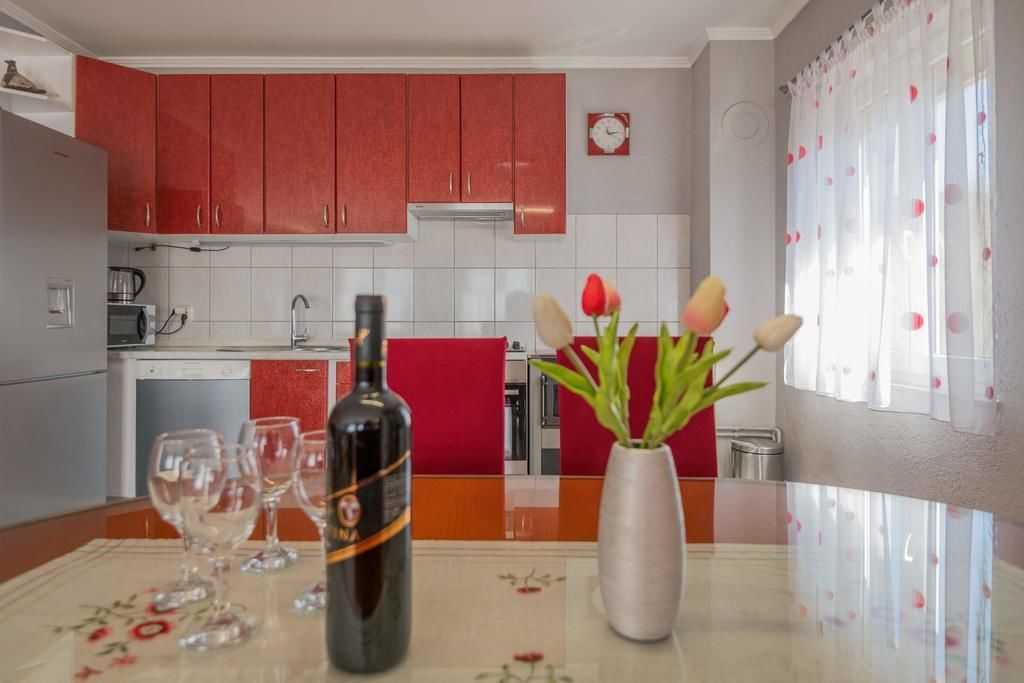 A kitchen with red cabinets, a white tiled backsplash, and a clock on the wall.