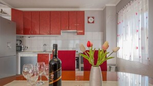 A kitchen with red cabinets, a white tiled backsplash, and a clock on the wall. - Village House Imotski (Imotski)