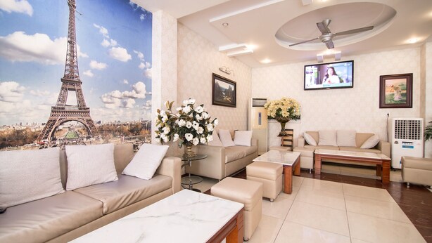 Una sala de estar con un gran mural de la Torre Eiffel, un conjunto de sofá, una mesa de centro y un televisor.