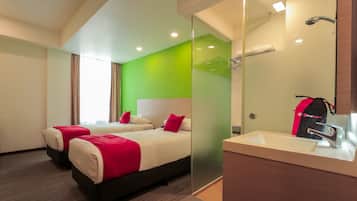 A hotel room with two beds, a large mirror, a sink, and a green accent wall.