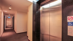 A hotel hallway with an elevator, a sign indicating no ice lifting in case of fire, and a wheelchair accessibility symbol. - RedDoorz Premium @ Balestier (Singapore)