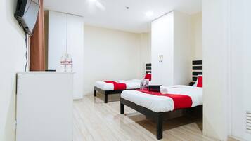 A hotel room with two beds, a small white refrigerator, and a television mounted on the wall.