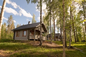 A cabin with a porch, surrounded by tall trees and a clear sky. - Holiday Village Kukkapää (Sulkava)