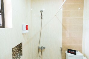 A bathroom with a shower, toilet, and a RedDoorz package on the toilet. - RedDoorz Premium @ Outlook Drive (Baguio)